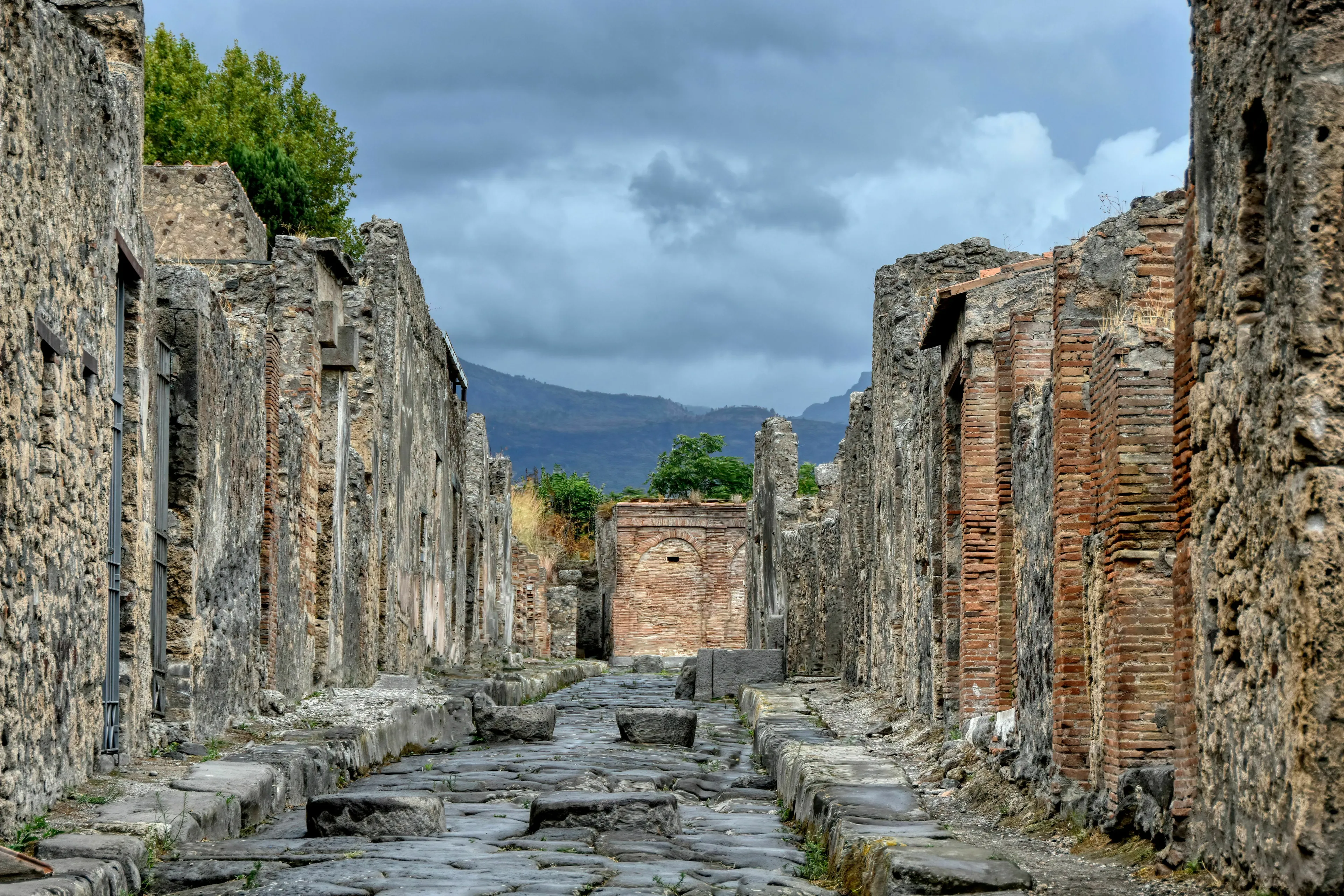 Ancient city of Pompeii ruins, destroyed by a Mount, with a cloudy sky overhead.