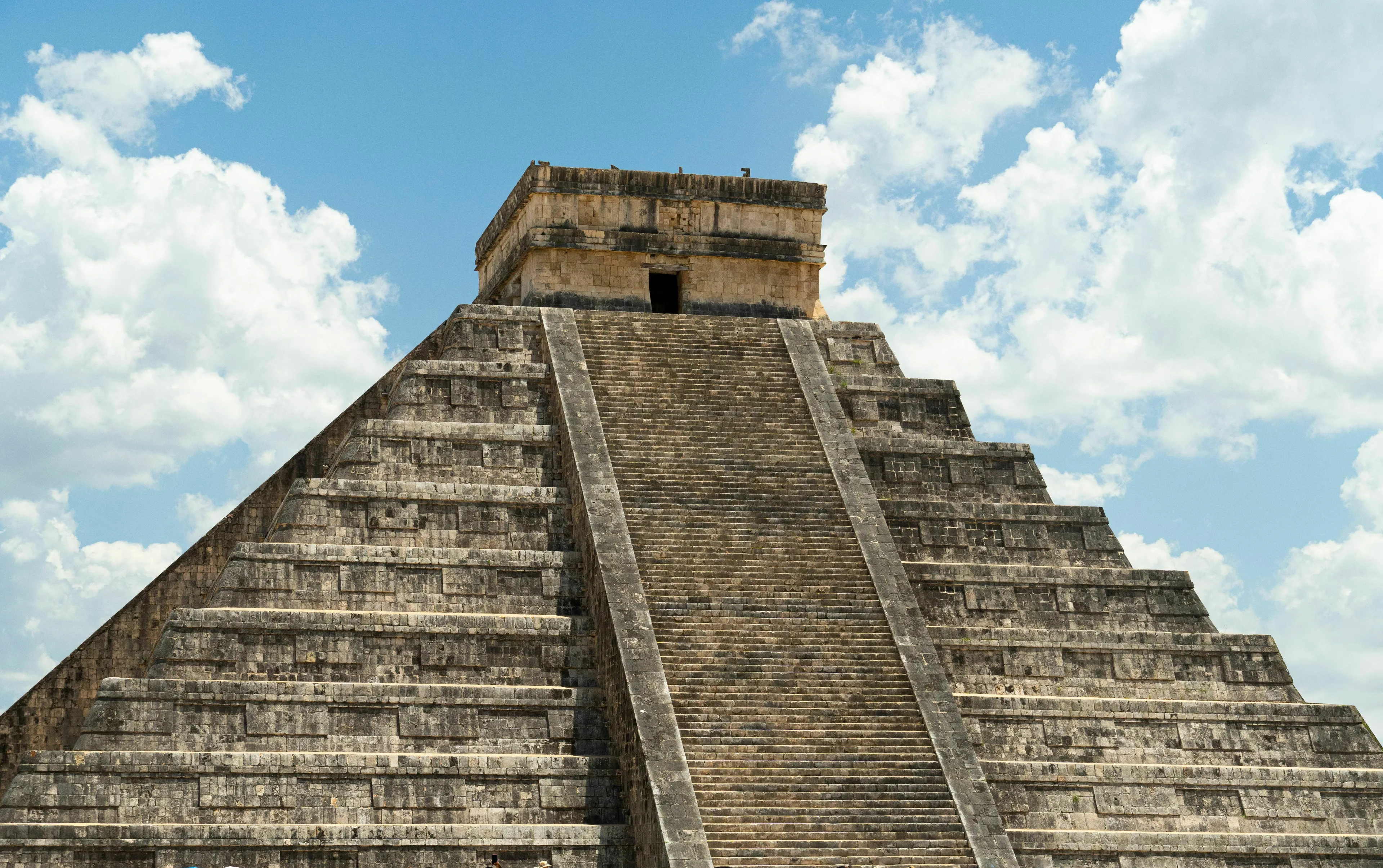 Pub Trivia Quiz: A grand landmark, the ancient Chichen Itza pyramid, under a bright blue sky with white clouds.