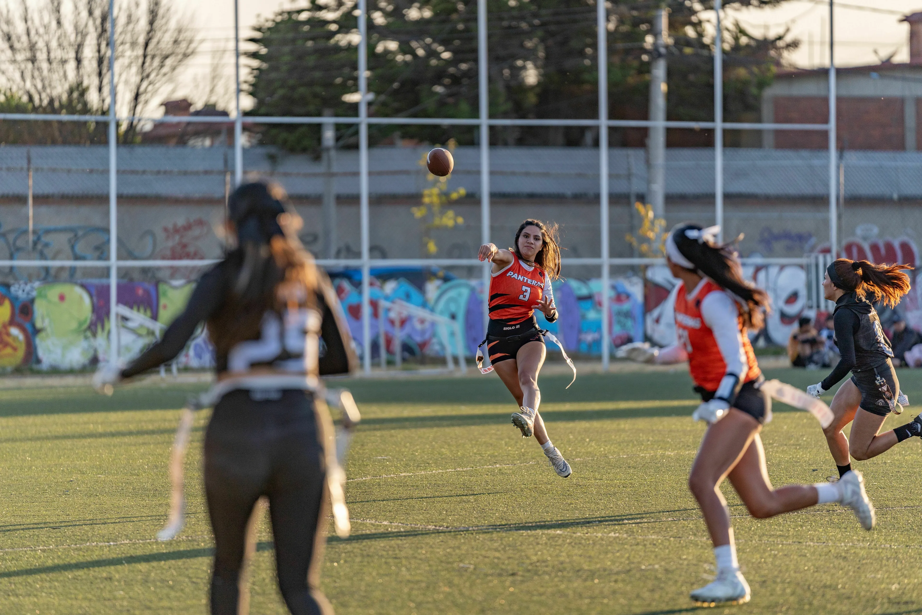 Pub Trivia Quiz: American football touchdown action, a woman throwing a football during a flag football game.