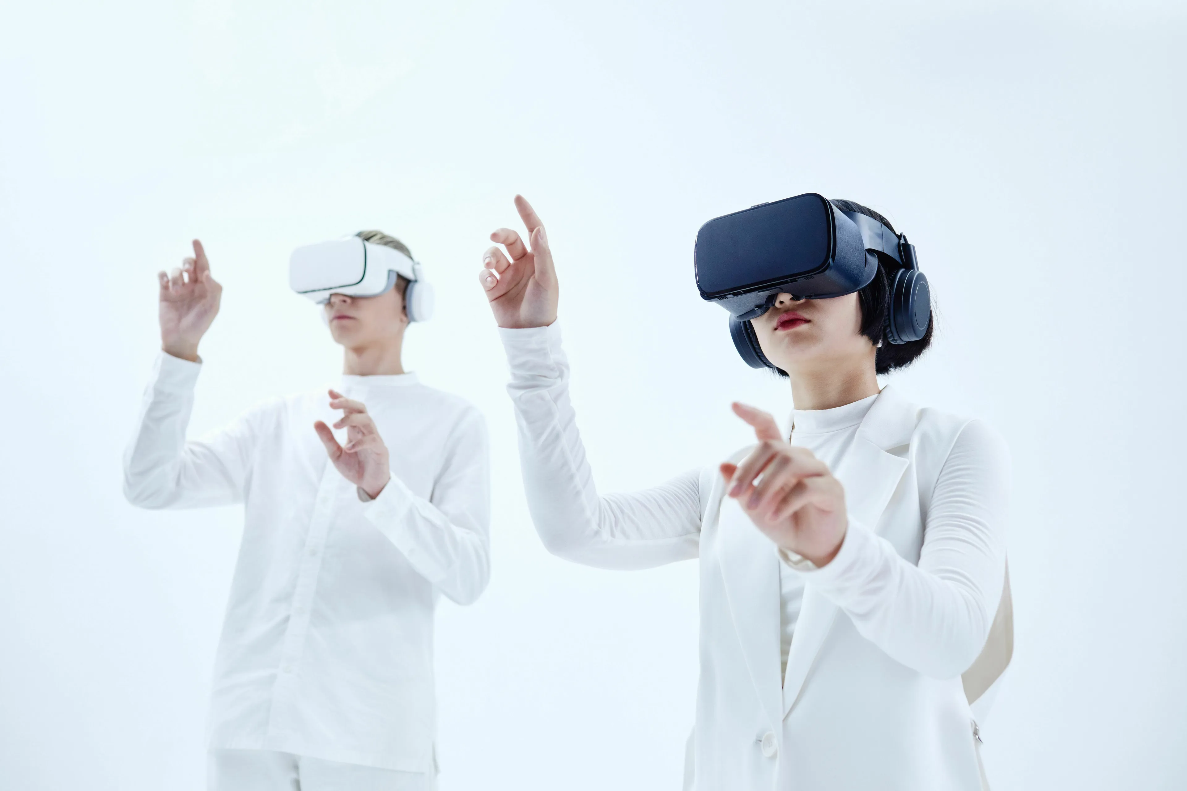 Two individuals wearing VR headsets, interacting with virtual technology in a bright, futuristic setting.