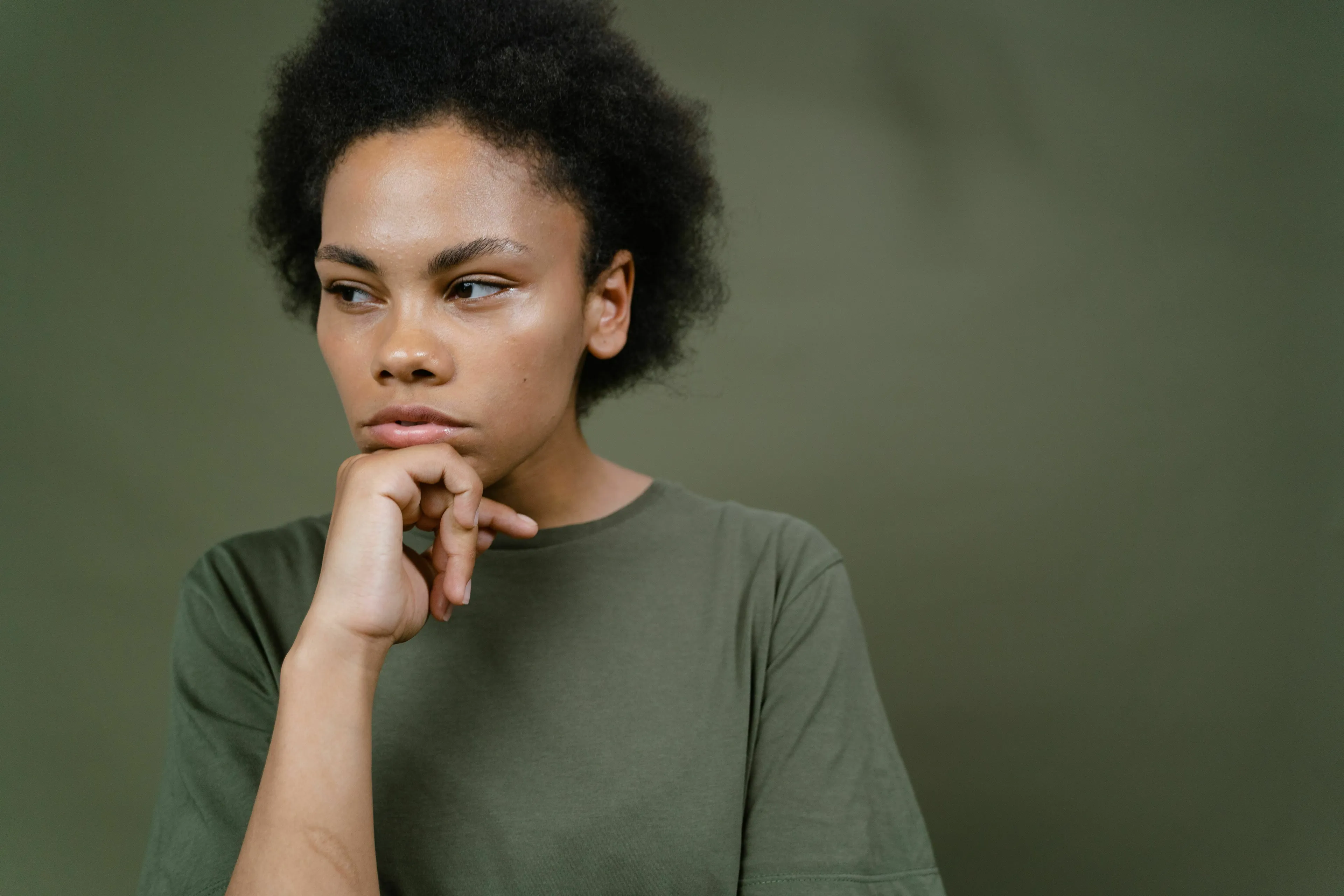 Young person with afro-textured hair looking thoughtful, hand on chin, for a Which Ancient Civilization Would You Have Thrived In quiz question.