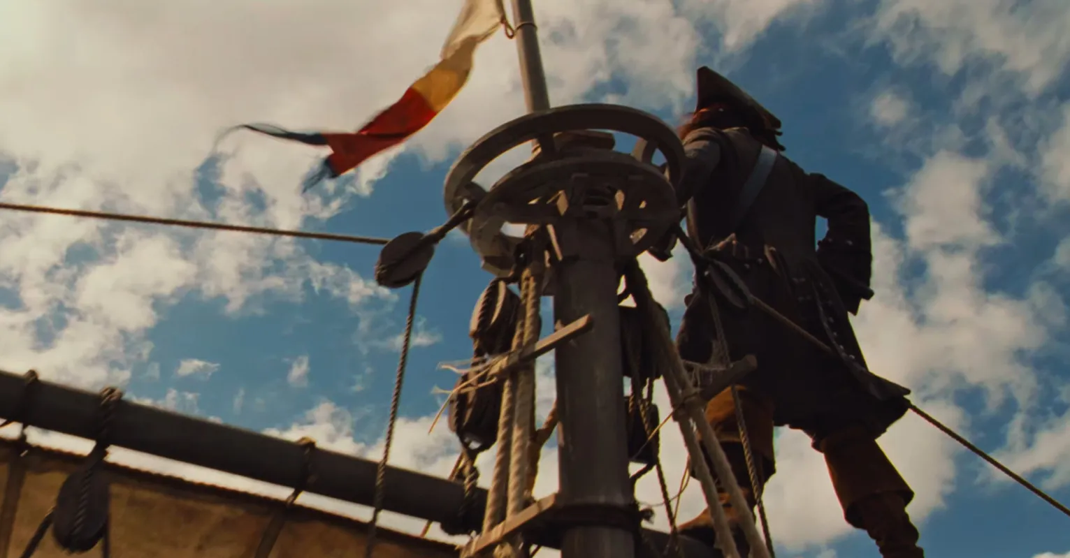 A pirate character, Jack Sparrow, stands on a ship's mast against a blue sky with clouds, a flag waving.