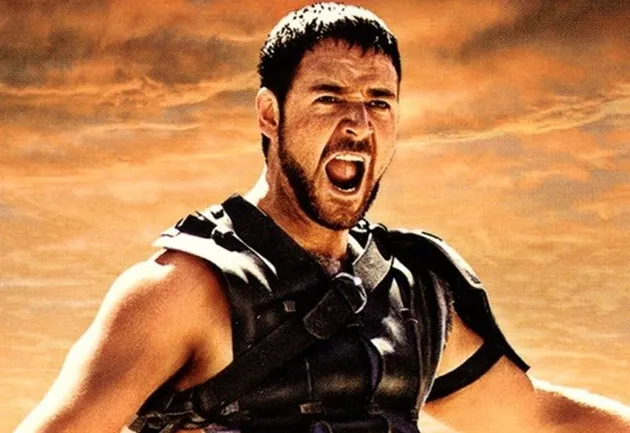 Close-up of Gladiator, Russell Crowe, roaring in a movie scene with an orange, fiery background.