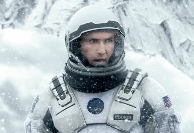 Matthew McConaughey as Cooper in Interstellar, wearing a space suit in a snowy, desolate landscape.