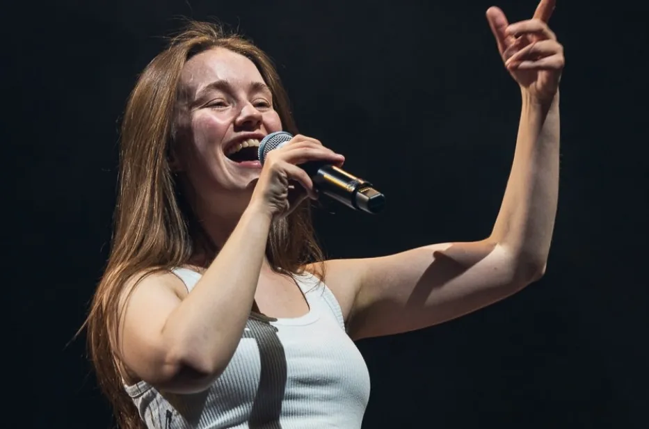 Sigrid, a musician, smiling and singing into a microphone on stage. Is this Icelandic musician Sigrid?