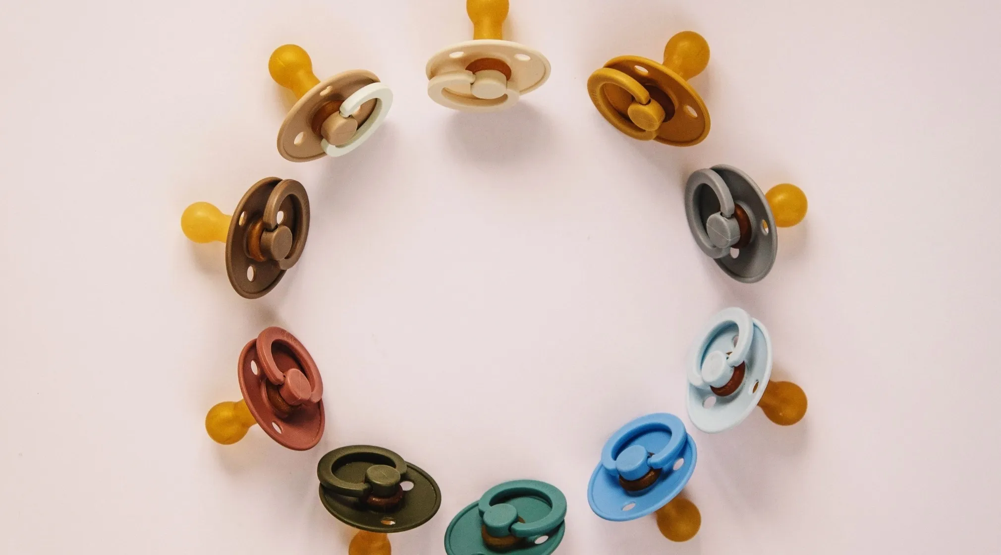 Various colored pacifiers, an American dummy, arranged in a circle on a white background, symbolizing language differences.