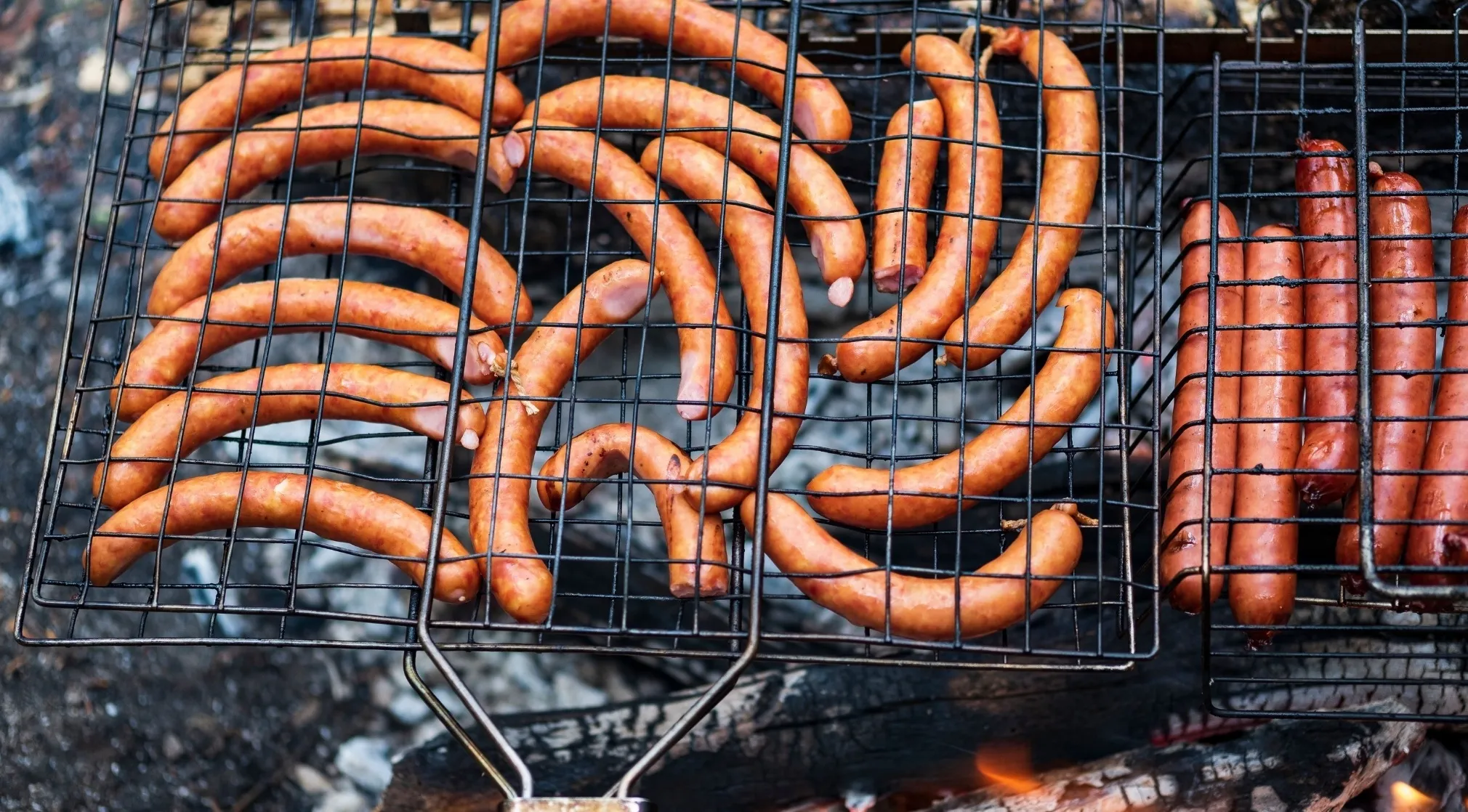 American Vs Brit Words: Sausages cooking on a grill. If a Brit ordered this for breakfast, they'd ask for a sausage, while an American would simply call it a sausage.