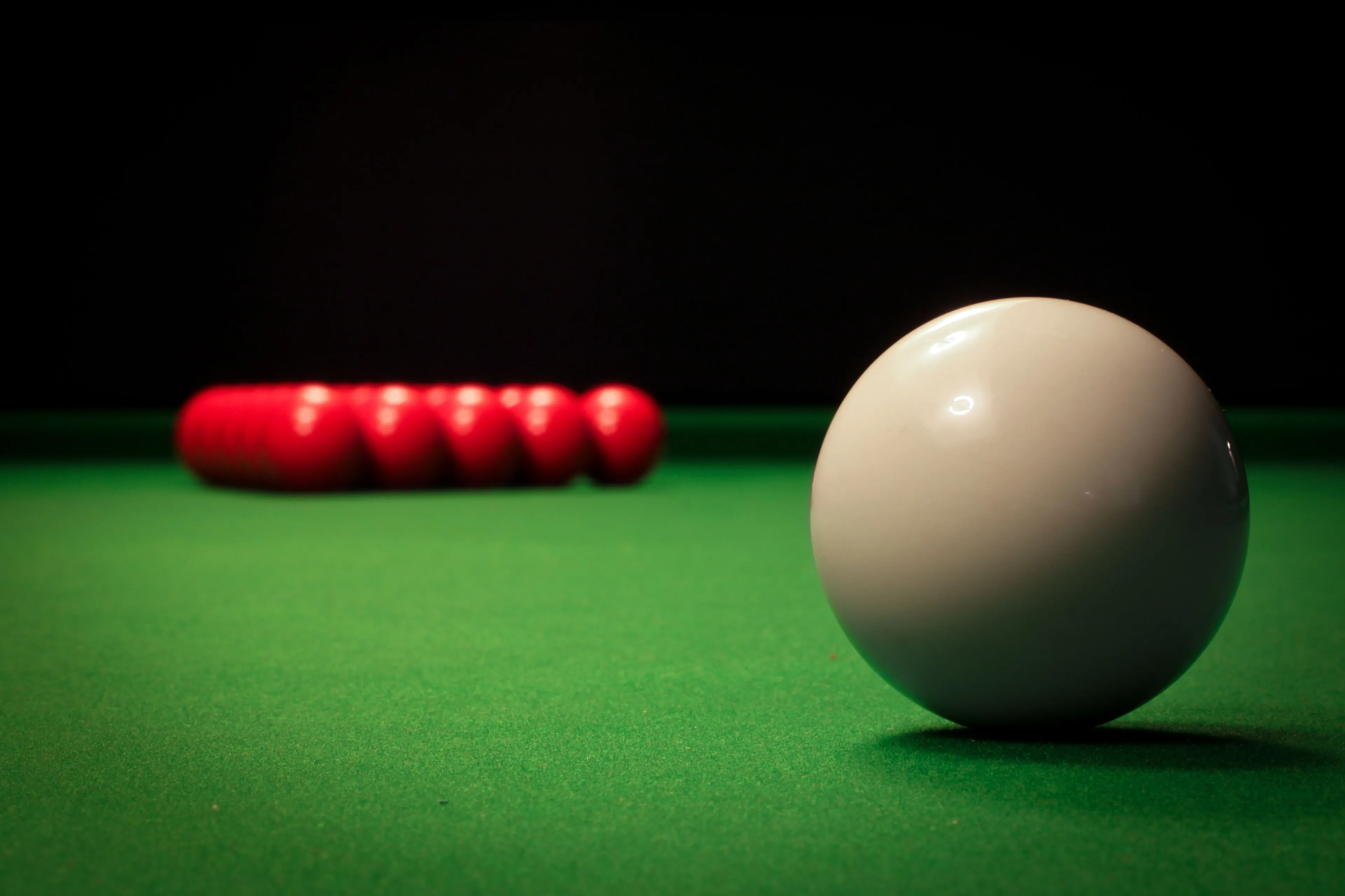 Pub trivia quiz: Woman playing pool, aiming for a shot, surrounded by colorful billiard balls.