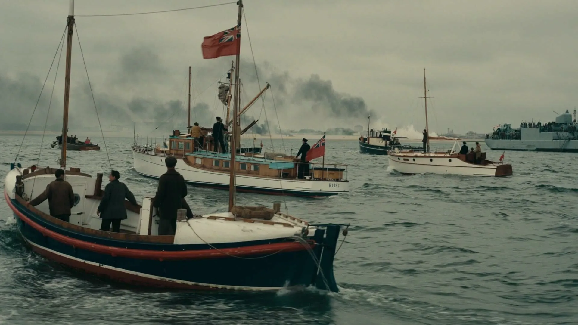Small boats on the sea under a cloudy sky, smoke in the distance. Guess the historic event from this movie still.