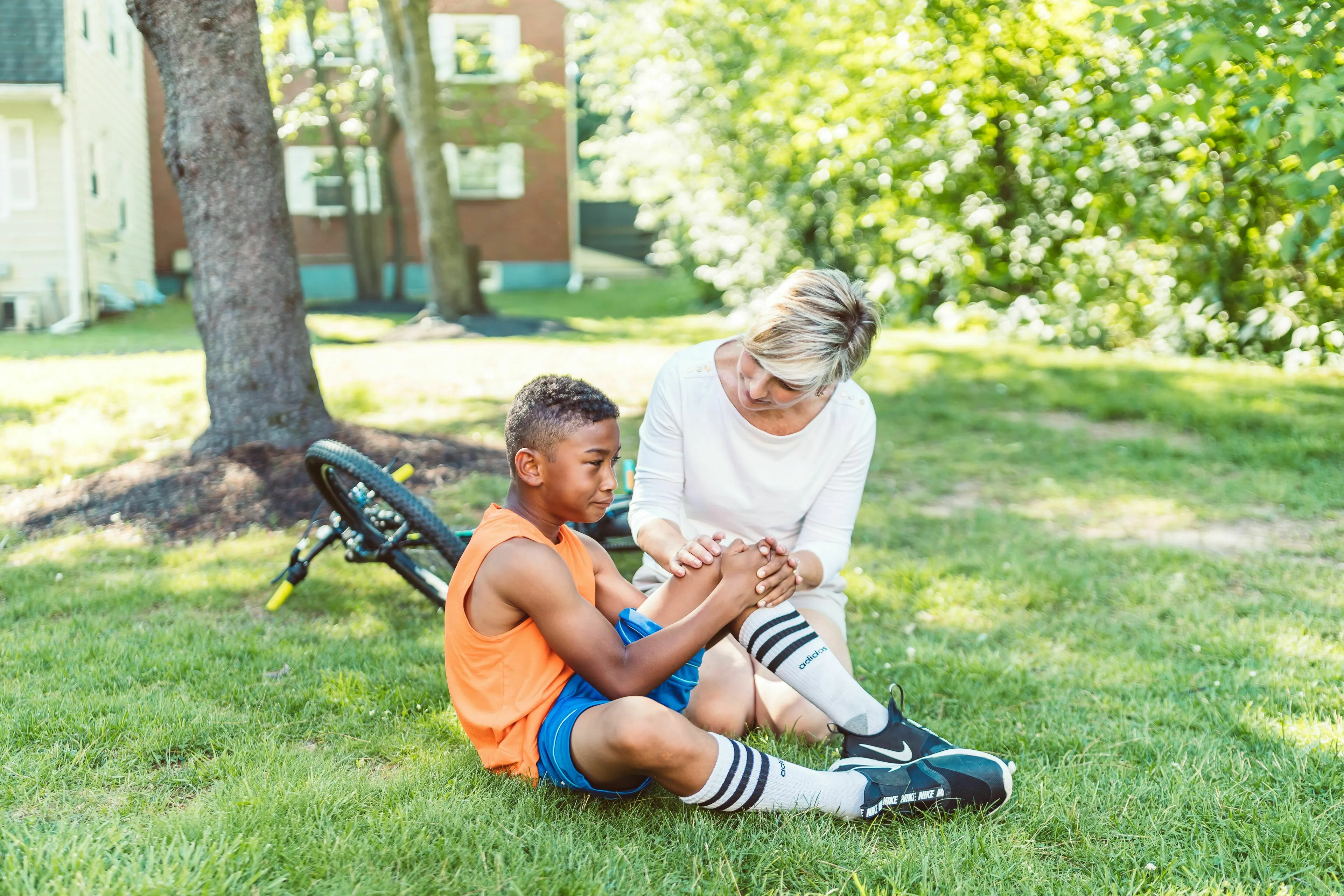Basic Medical Knowledge Quiz: An adult assisting a child who has fallen from a bike, holding his knee, illustrating blood clotting and preventing excessive bleeding.
