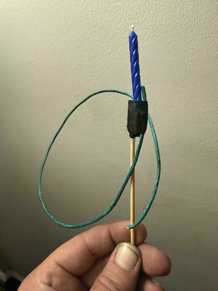 A blue birthday candle taped to a wooden skewer with a green string, a clever solution for random junk.