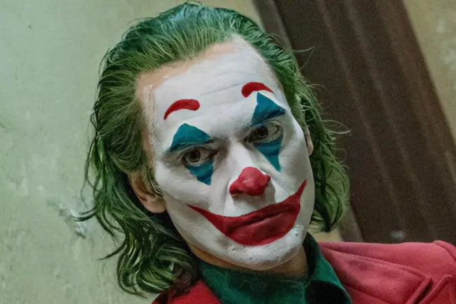 The Joker, a movie villain, in his iconic clown makeup, looking intensely at the camera.