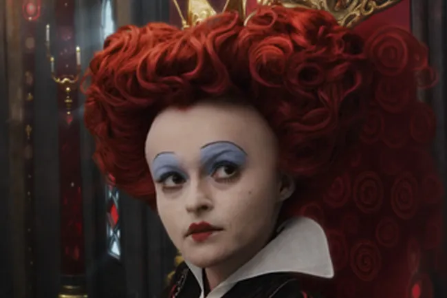 The Queen of Hearts, a movie villain, with a large red wig and blue eyeshadow.