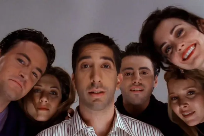 The iconic main cast of Friends looking down from above with happy expressions.