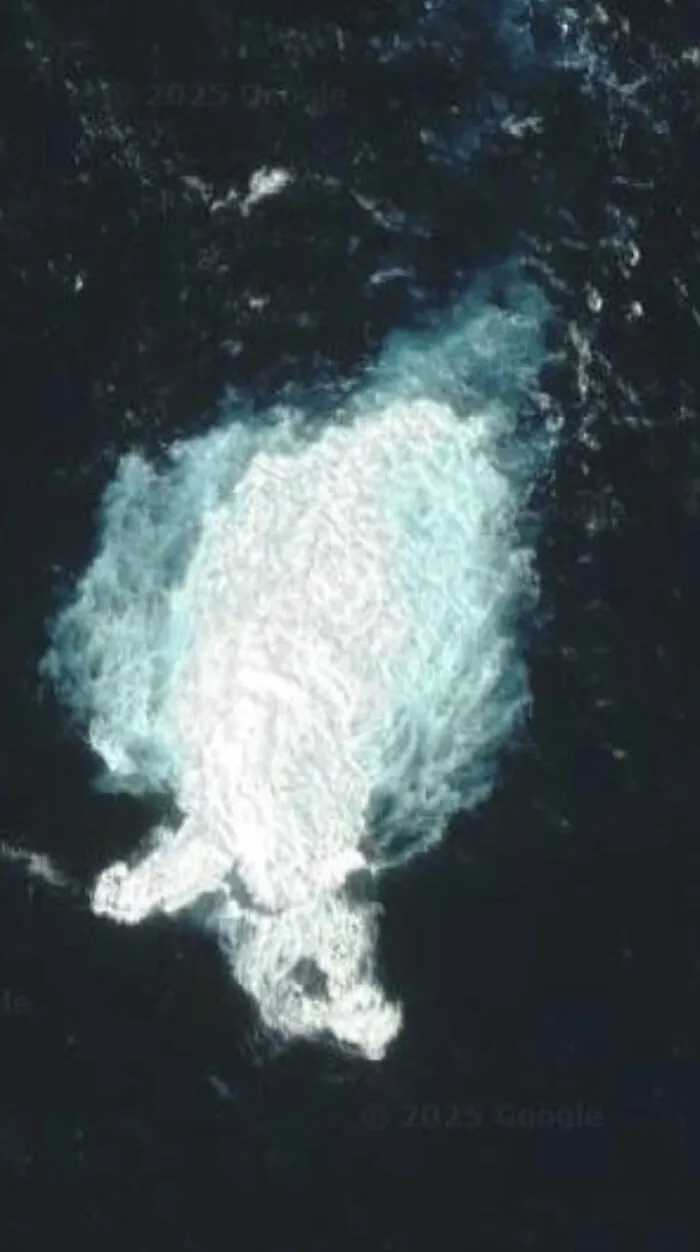 An aerial view from Google Street View showing a large, white, cloud-like shape in the dark ocean.