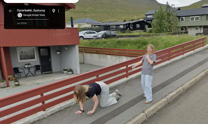 Two kids captured in a bizarre Google Street View photo, one crawling, the other pointing, on a residential street.