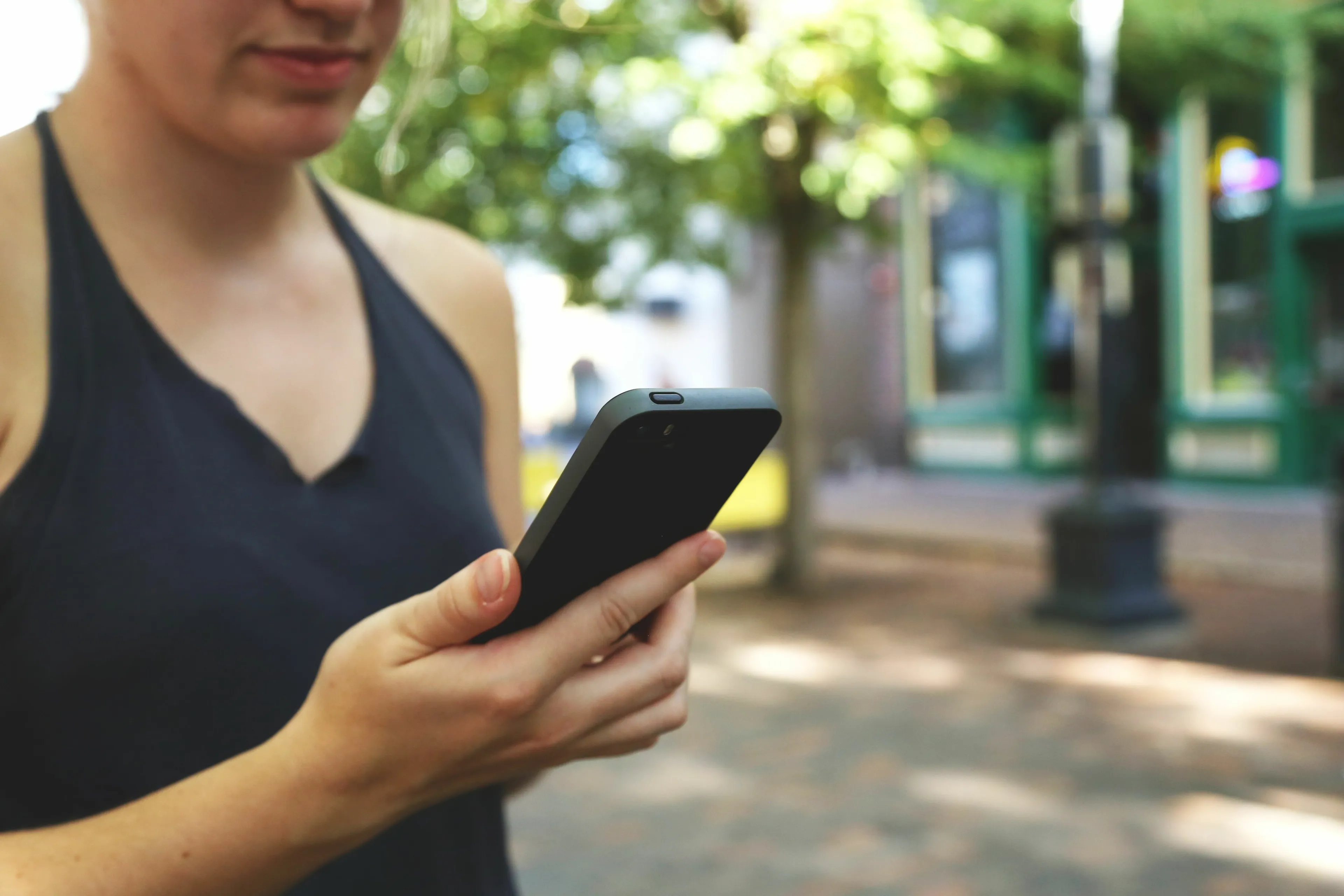 A woman looking at her phone, contemplating a last-minute invite and how brave she is.