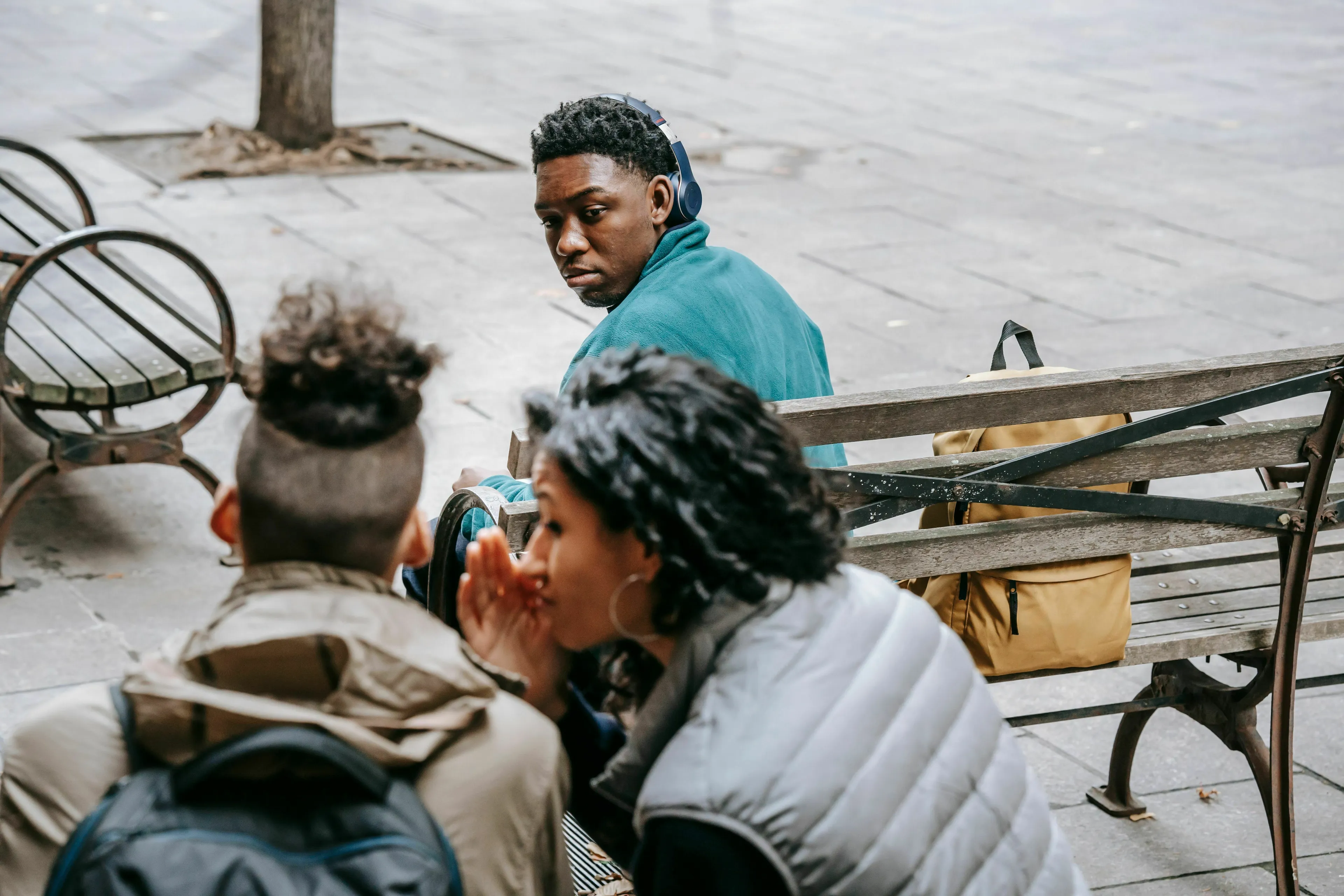 A young man with headphones on, looking back as two people whisper, reflecting what people get wrong about him.
