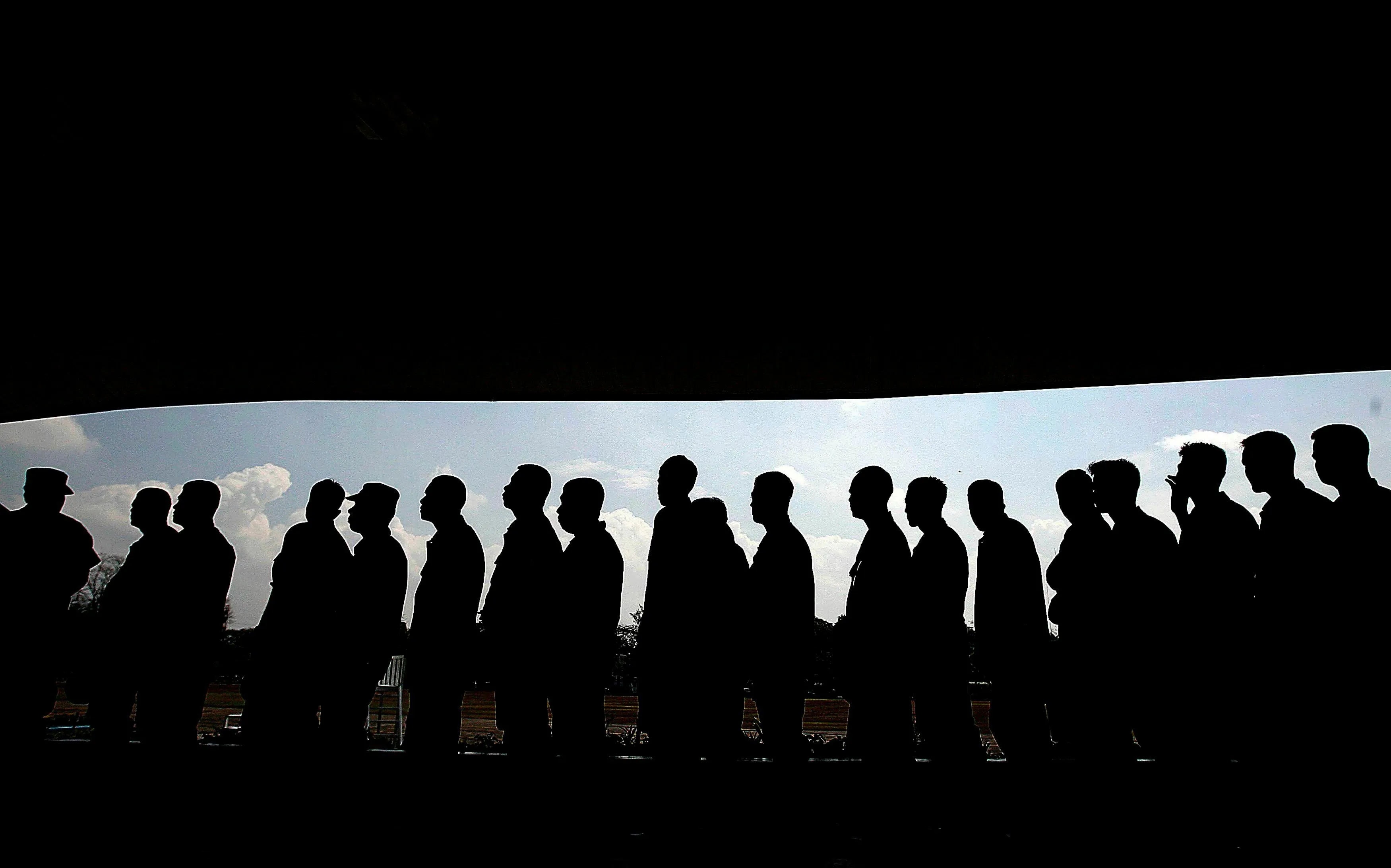 Silhouettes of people in a very long queue, illustrating bravery in handling delays.