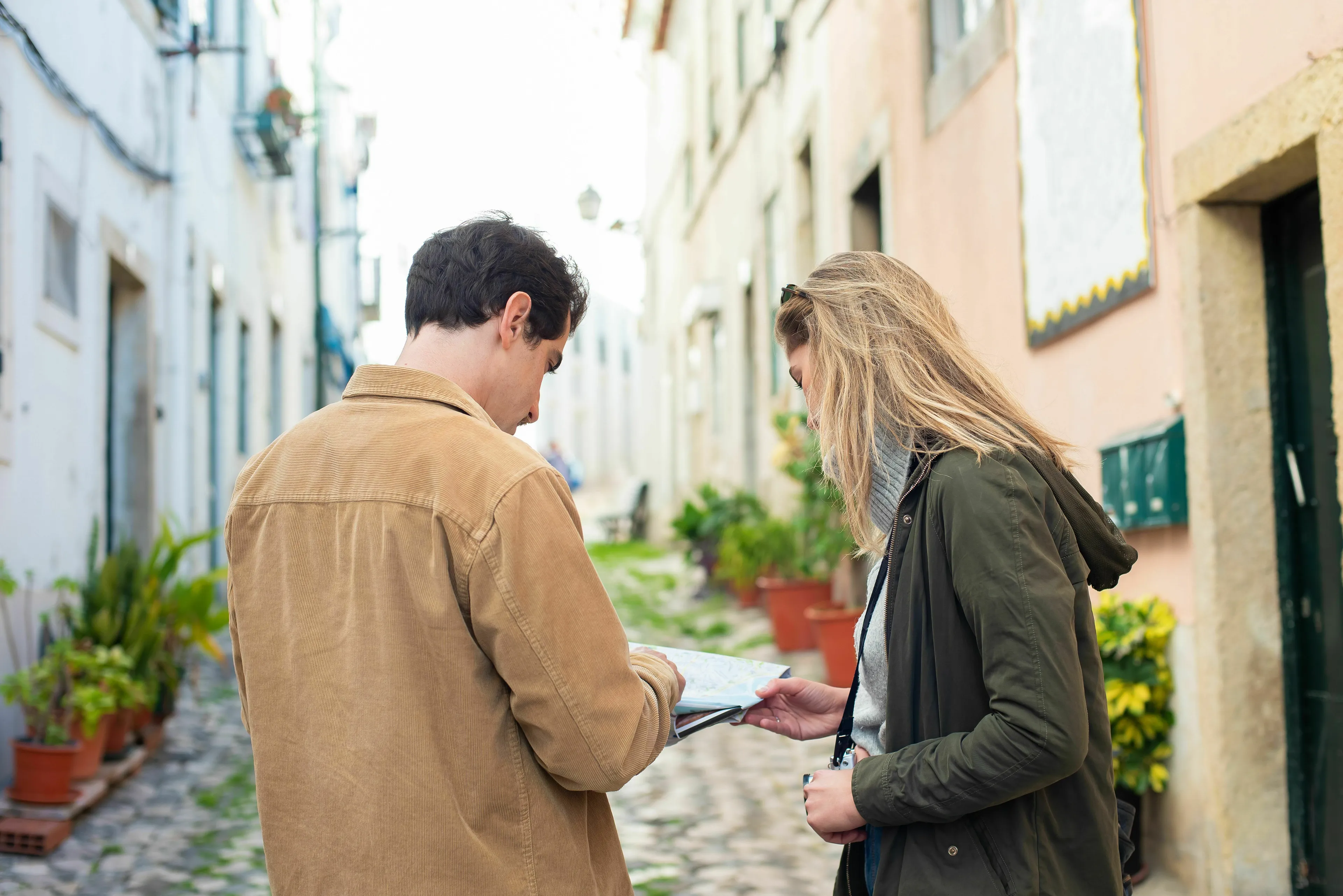 Travel companions studying a map on a charming street, contemplating a spontaneous adventure.