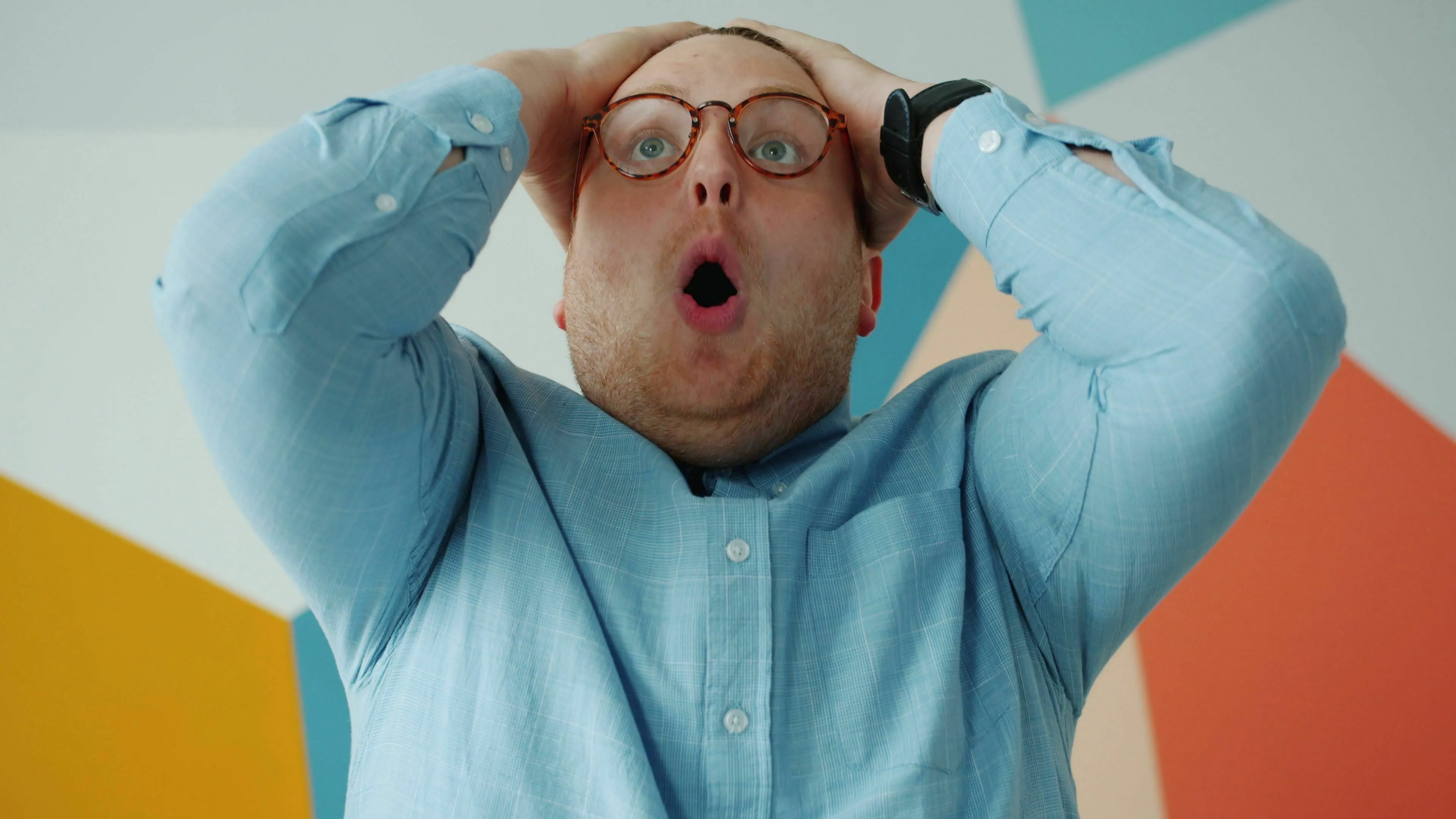Man with glasses, hands on head, mouth open in shock or surprise, depicting forgetting someone's name.