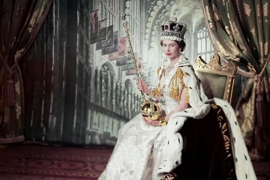 Queen Elizabeth II in her coronation gown, crown, and holding the orb and scepter, marking her coronation.