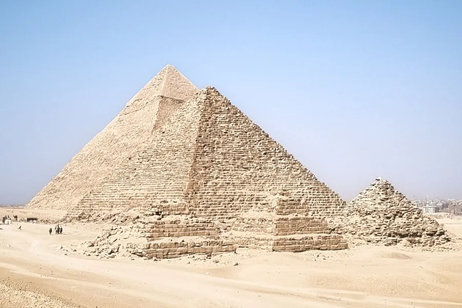 A wide shot of the Great Pyramid of Giza under a clear sky, showcasing its ancient construction.