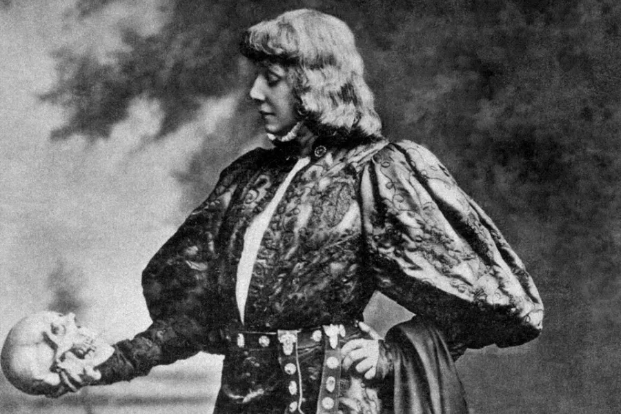 A black and white photo of a woman in elaborate costume, holding a skull, depicting the premiere of Shakespeare's Hamlet.