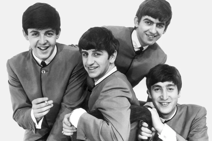 The Beatles are formed, a black and white photo of the four smiling band members in suits.
