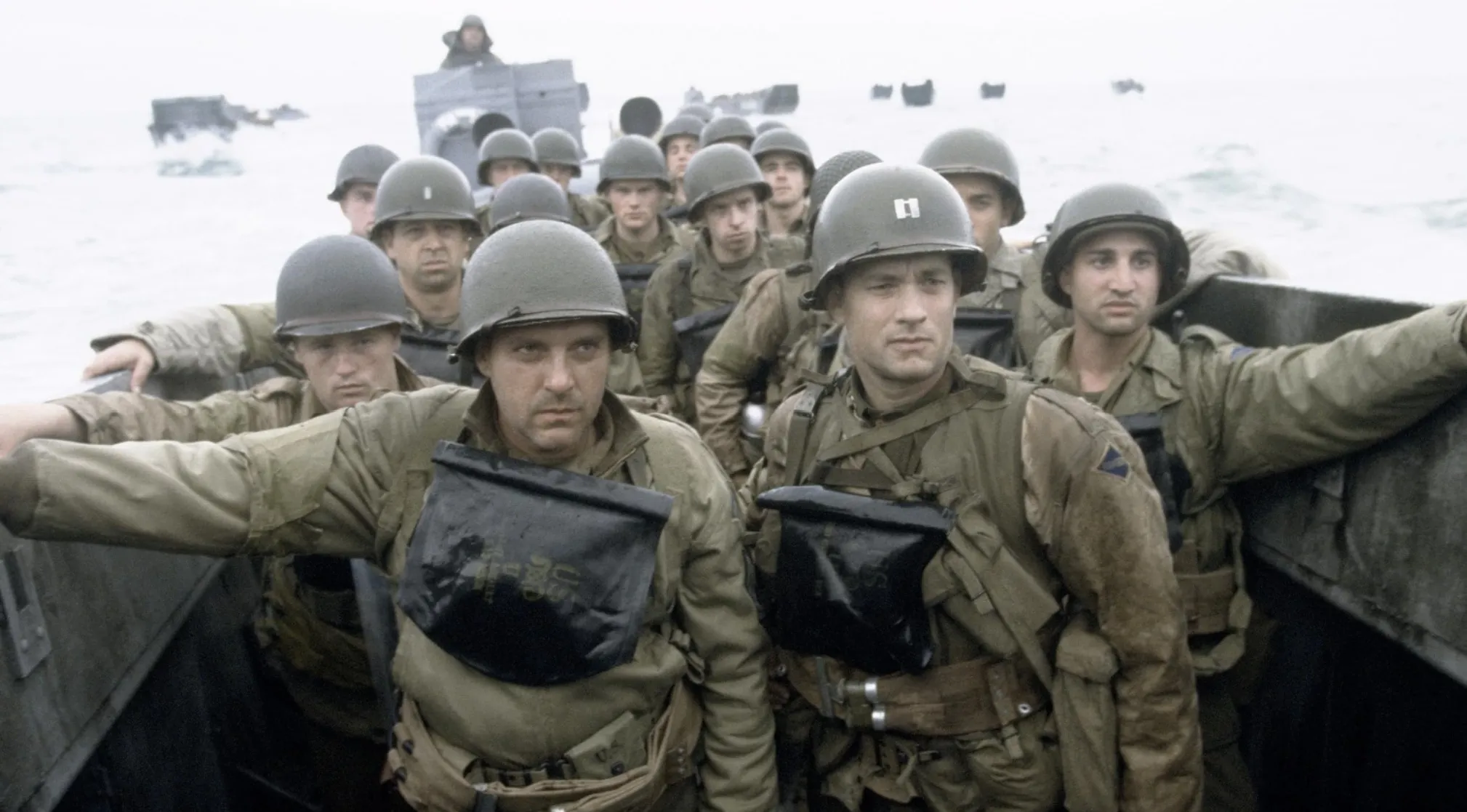 Soldiers in a landing craft, including Tom Hanks, during a scene from Saving Private Ryan, perfect for 80s & 90s movie trivia.