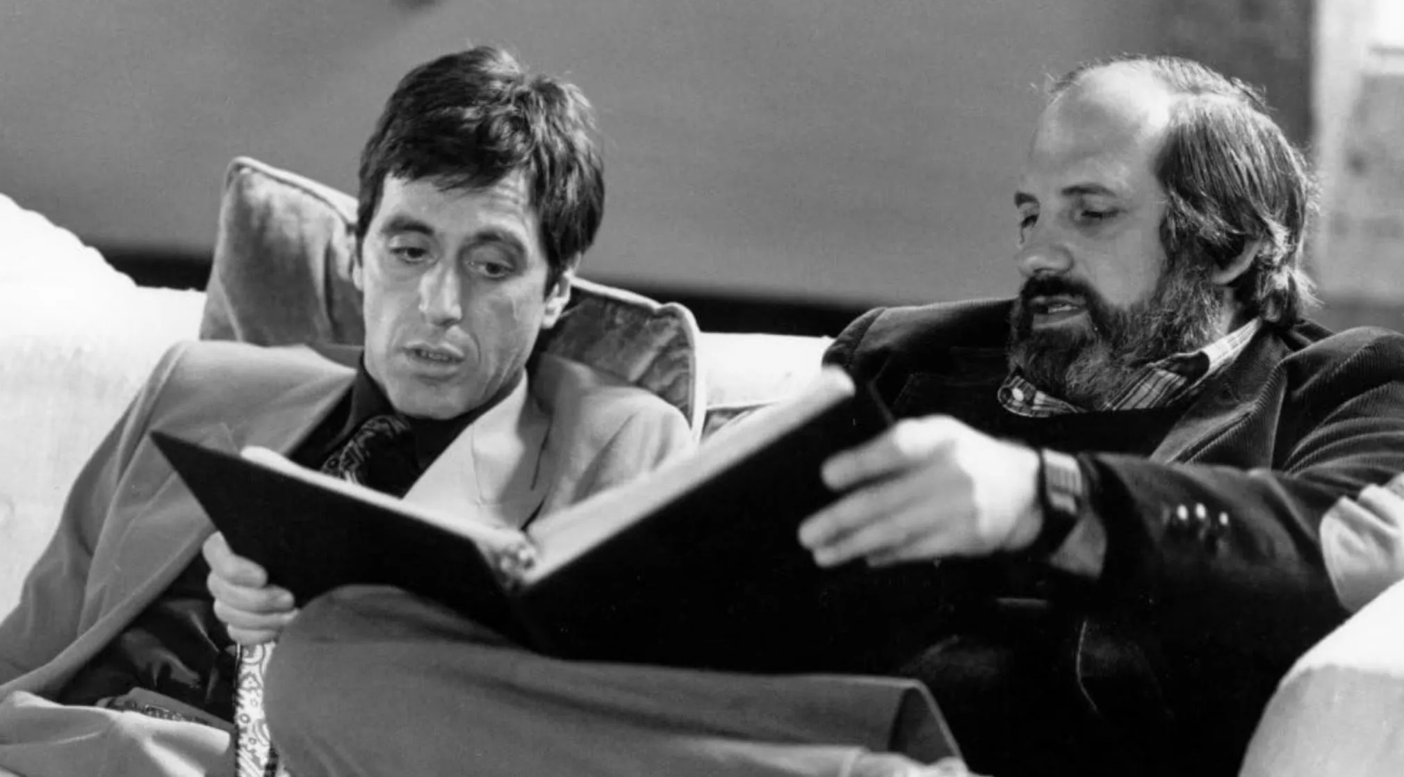 Black and white photo of Al Pacino and director Brian De Palma discussing a script for an 80s & 90s movie trivia.