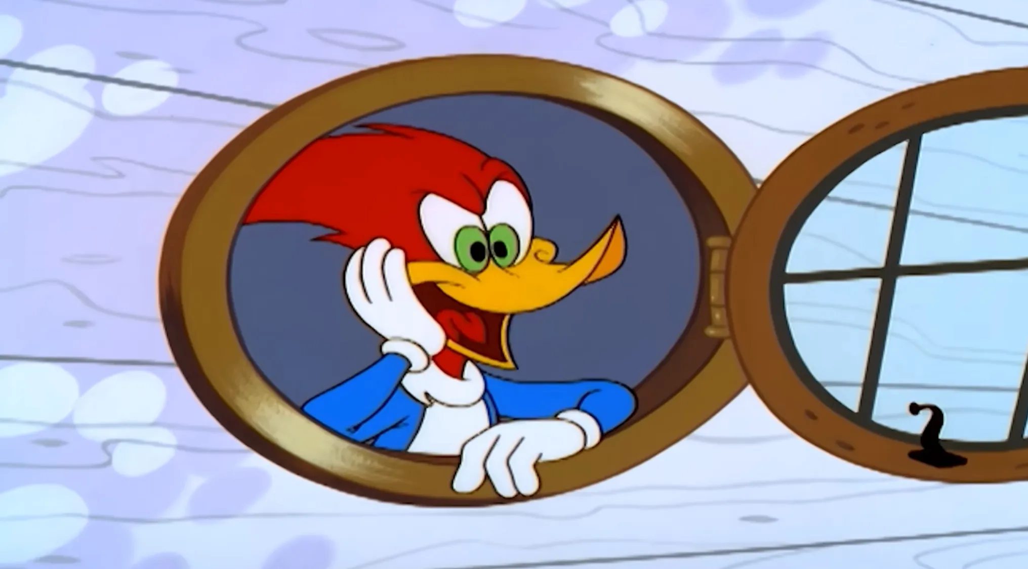 Woody Woodpecker looking out from a round window, with his characteristic red crest, green eyes, and blue jacket.