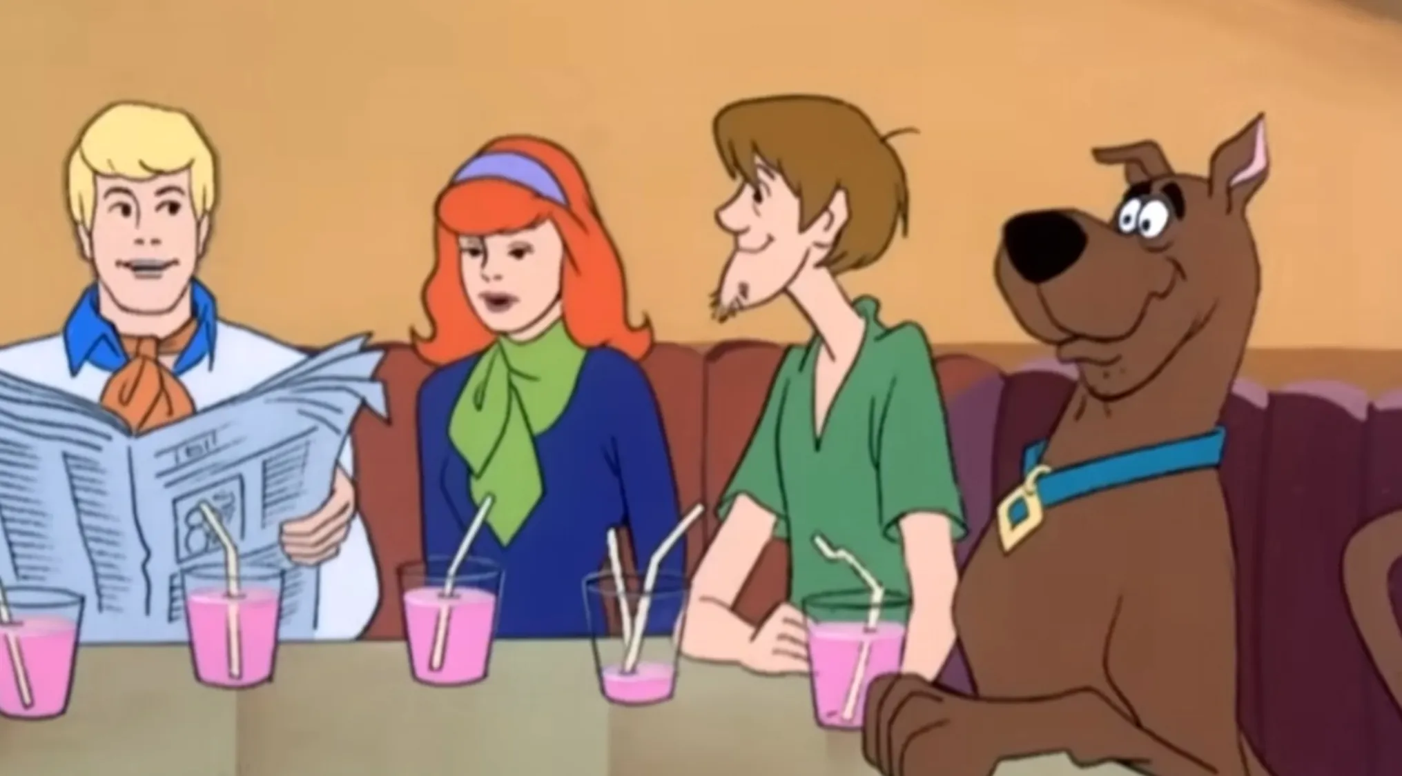 Fred, Daphne, Shaggy, and Scooby-Doo from Saturday Morning Cartoons are sitting at a table.