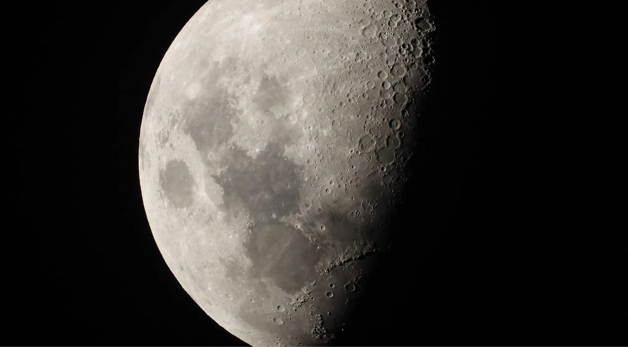 A detailed close-up of the Moon, showing numerous craters and textured surface, relevant to the first person to walk on the Moon.