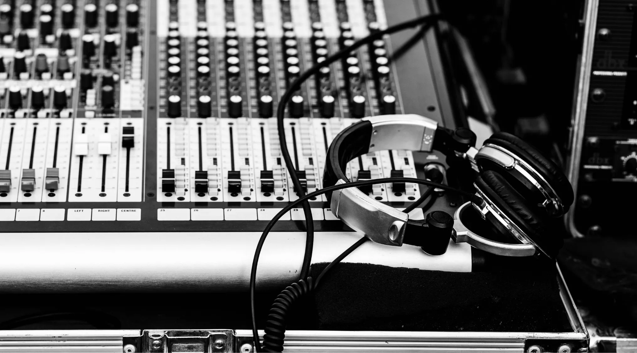 Black and white image of a sound mixer with headphones. Adjusting the music volume is key for sound quality.