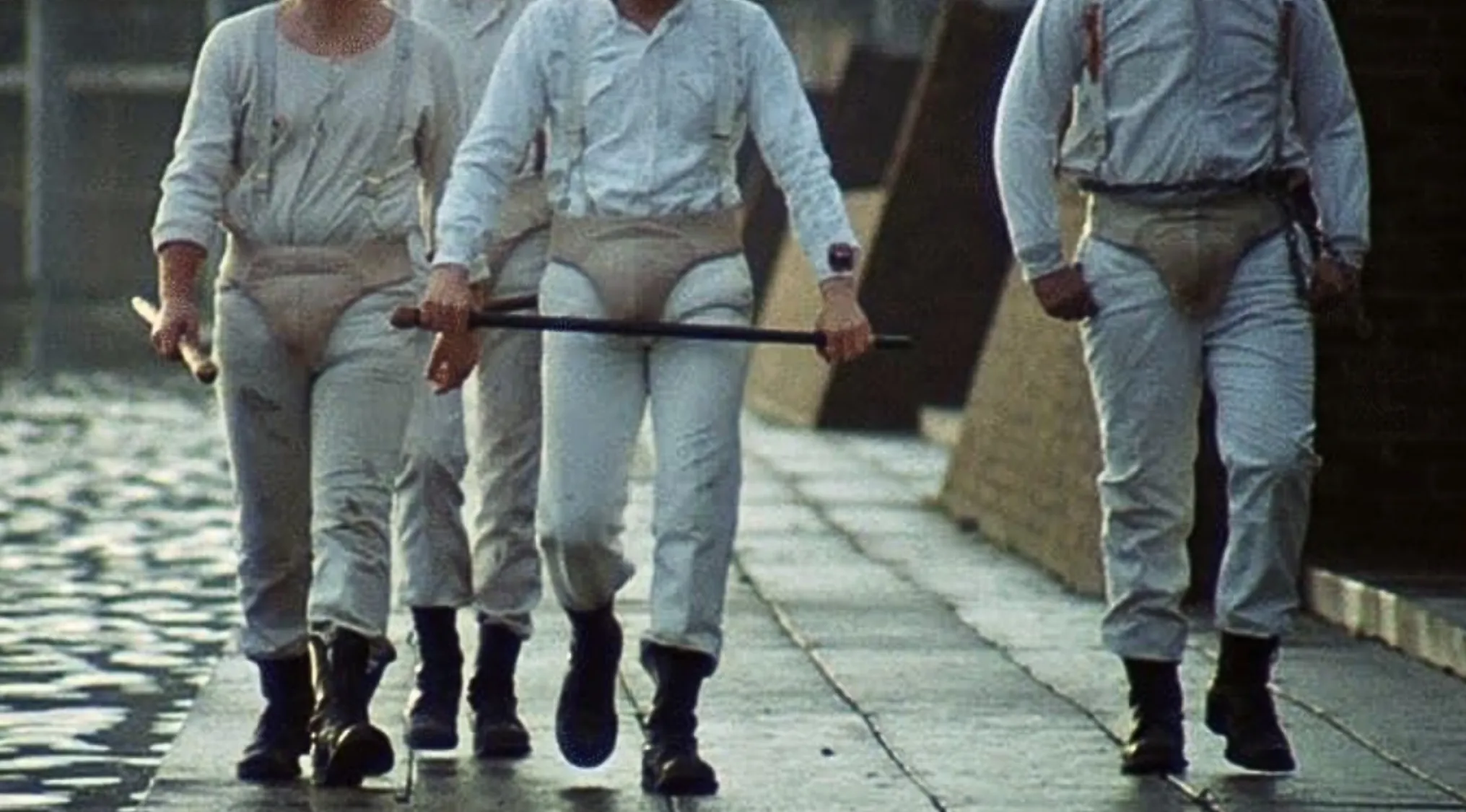 Three men in white jumpsuits and suspenders, classic movie outfits.