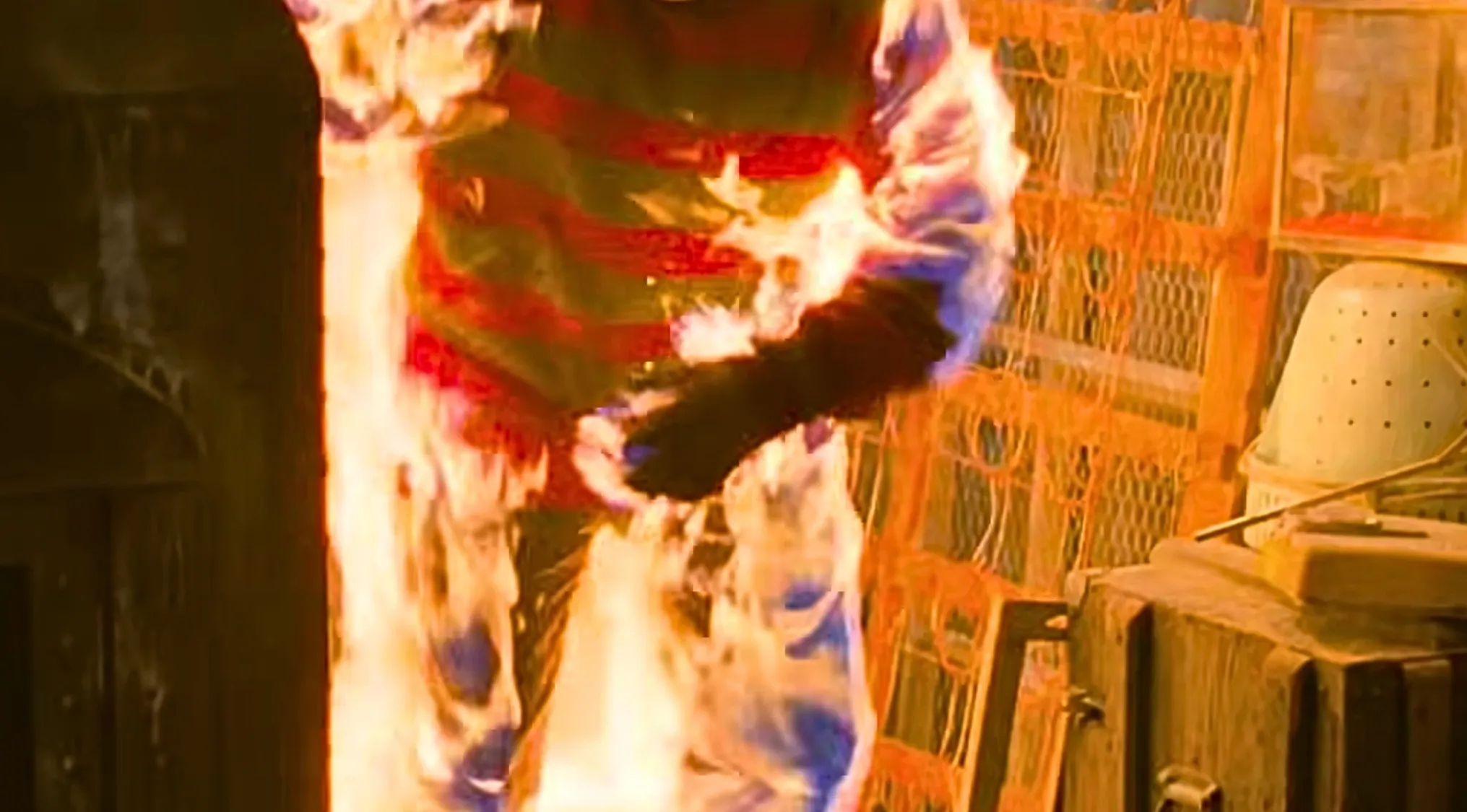 A horror movie outfit, a striped sweater on a figure engulfed in flames, from a movie with fashion sense.