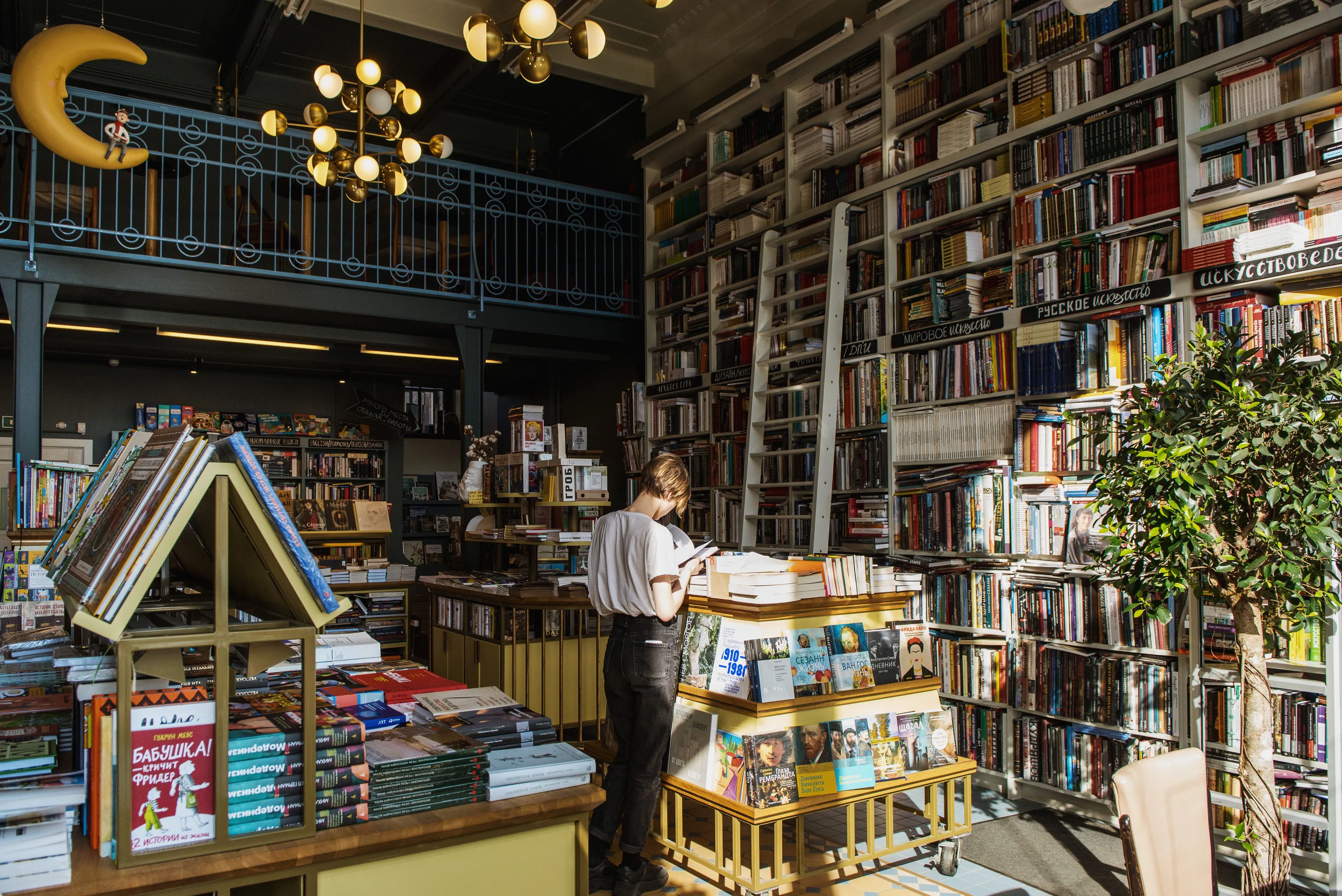 A person browsing books in a large, well-lit bookshop, a great place to spend a Sunday afternoon.