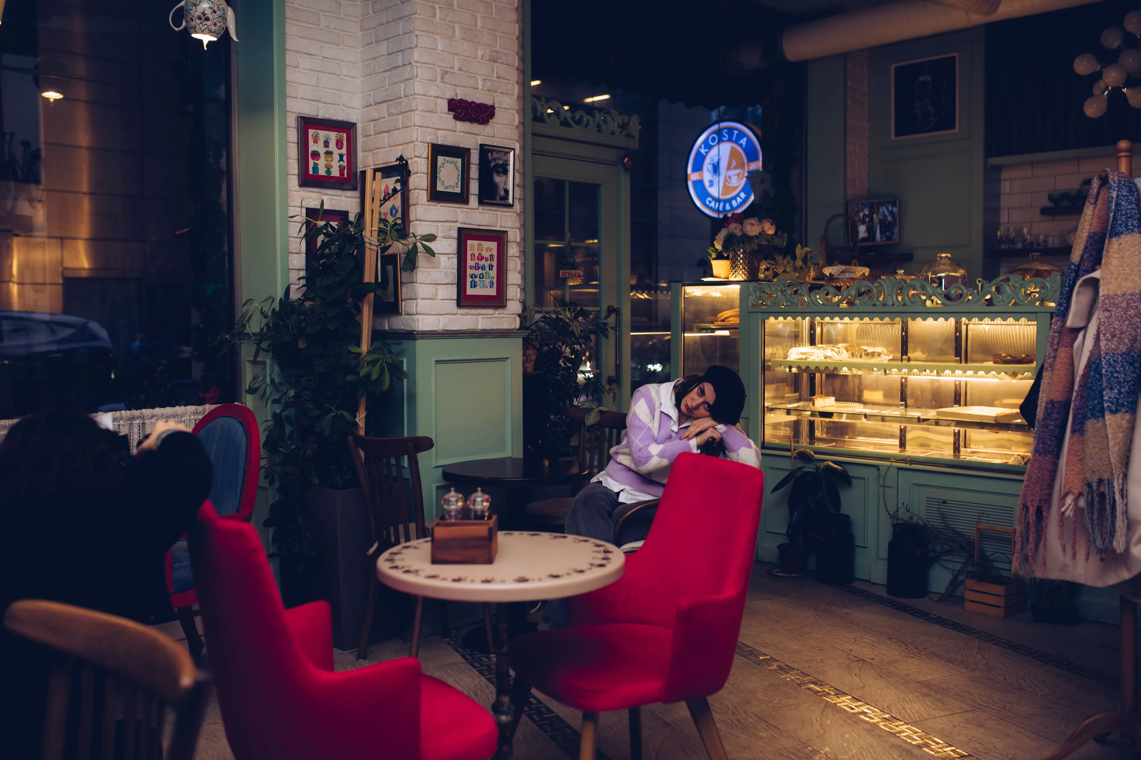 A person leaning on a table in a cozy cafe with red chairs, enjoying a quiet Sunday afternoon.