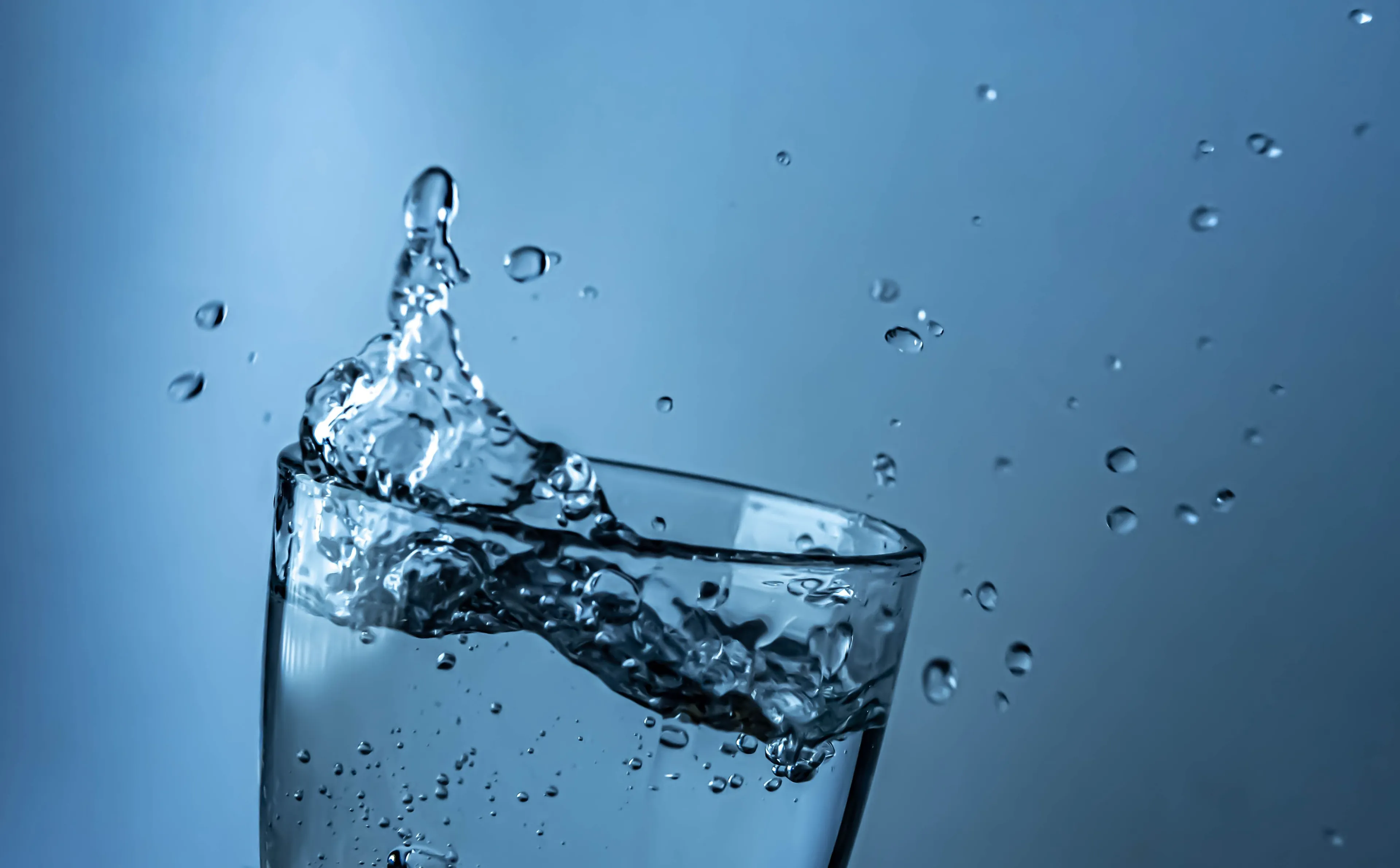 Clear water splashing out of a glass, suggesting a refreshing drink of water.