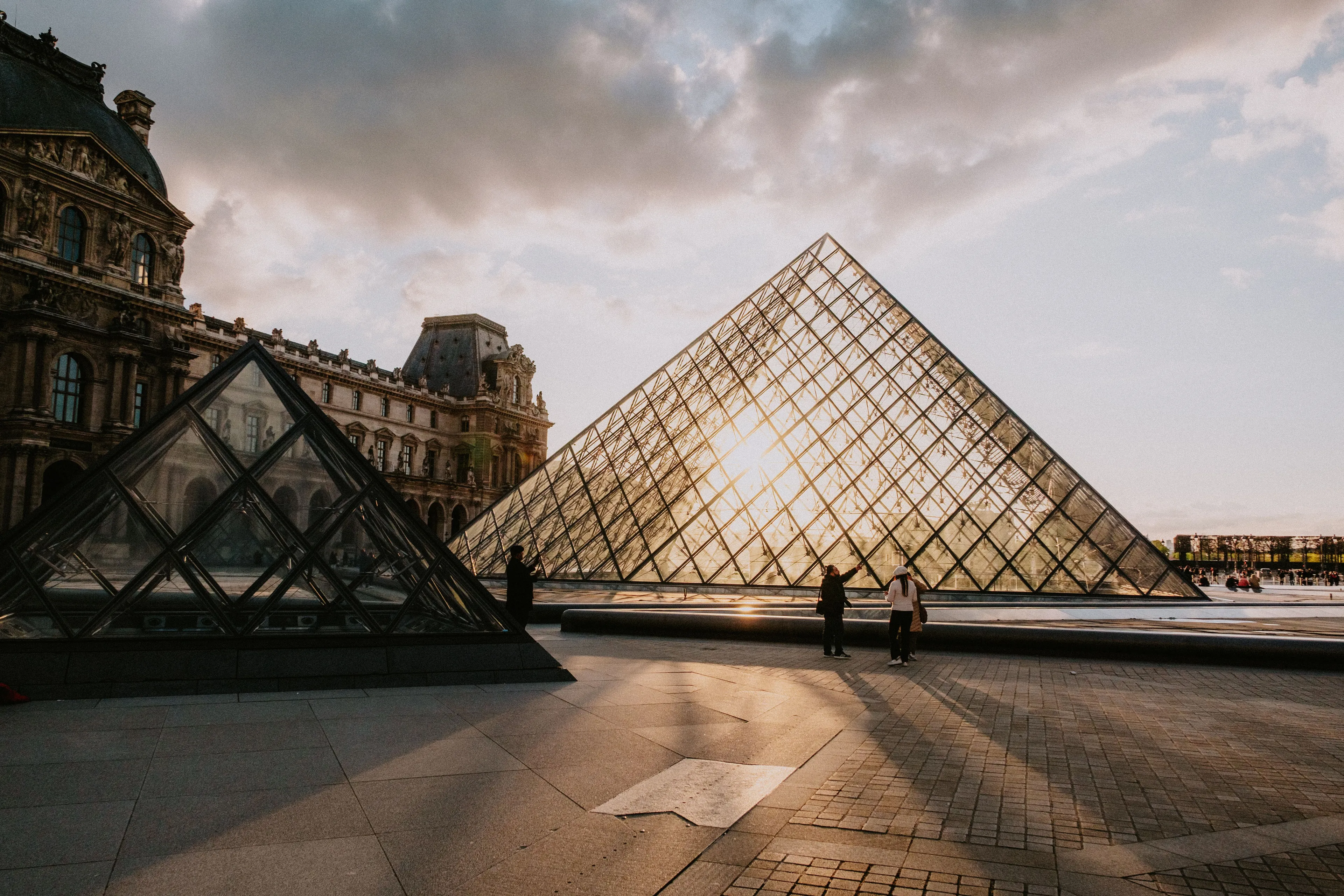 The Louvre, with its iconic glass pyramid, glows under the setting sun, inviting visitors to pick a place to visit.