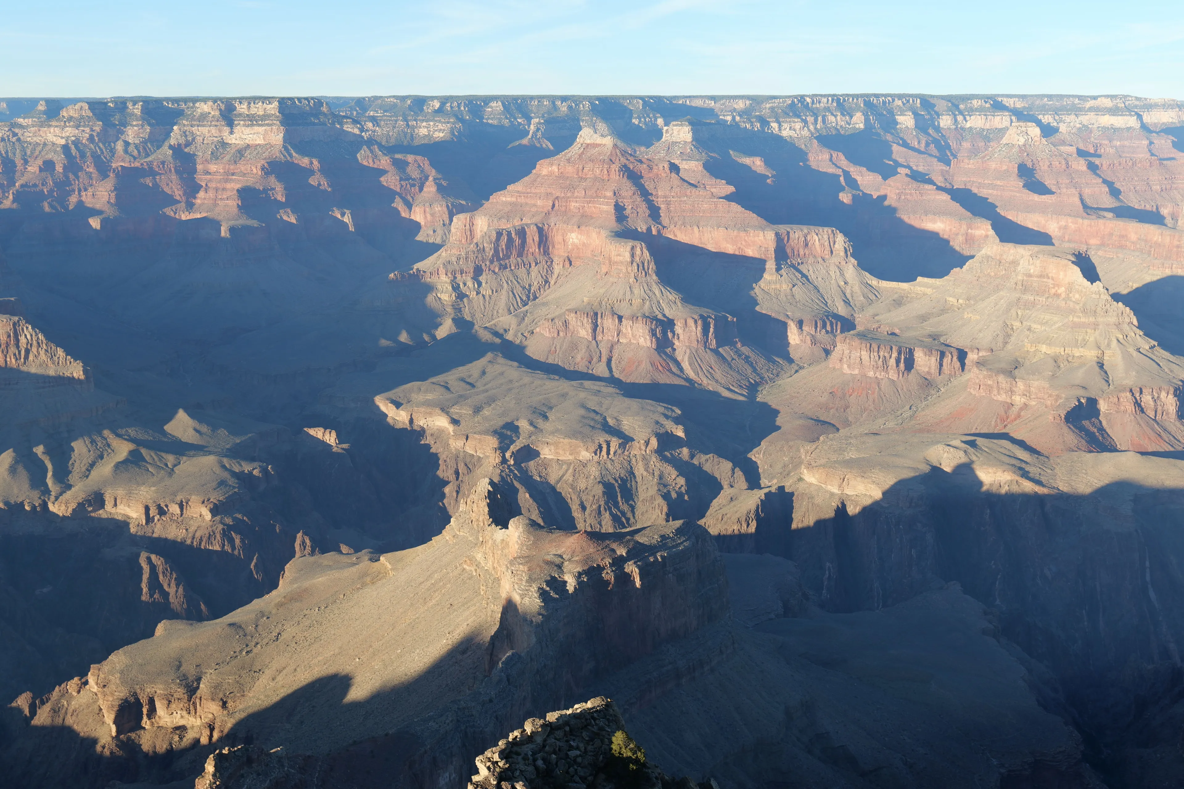 The vast landscape of The Grand Canyon bathed in sunlight, a majestic place to visit.