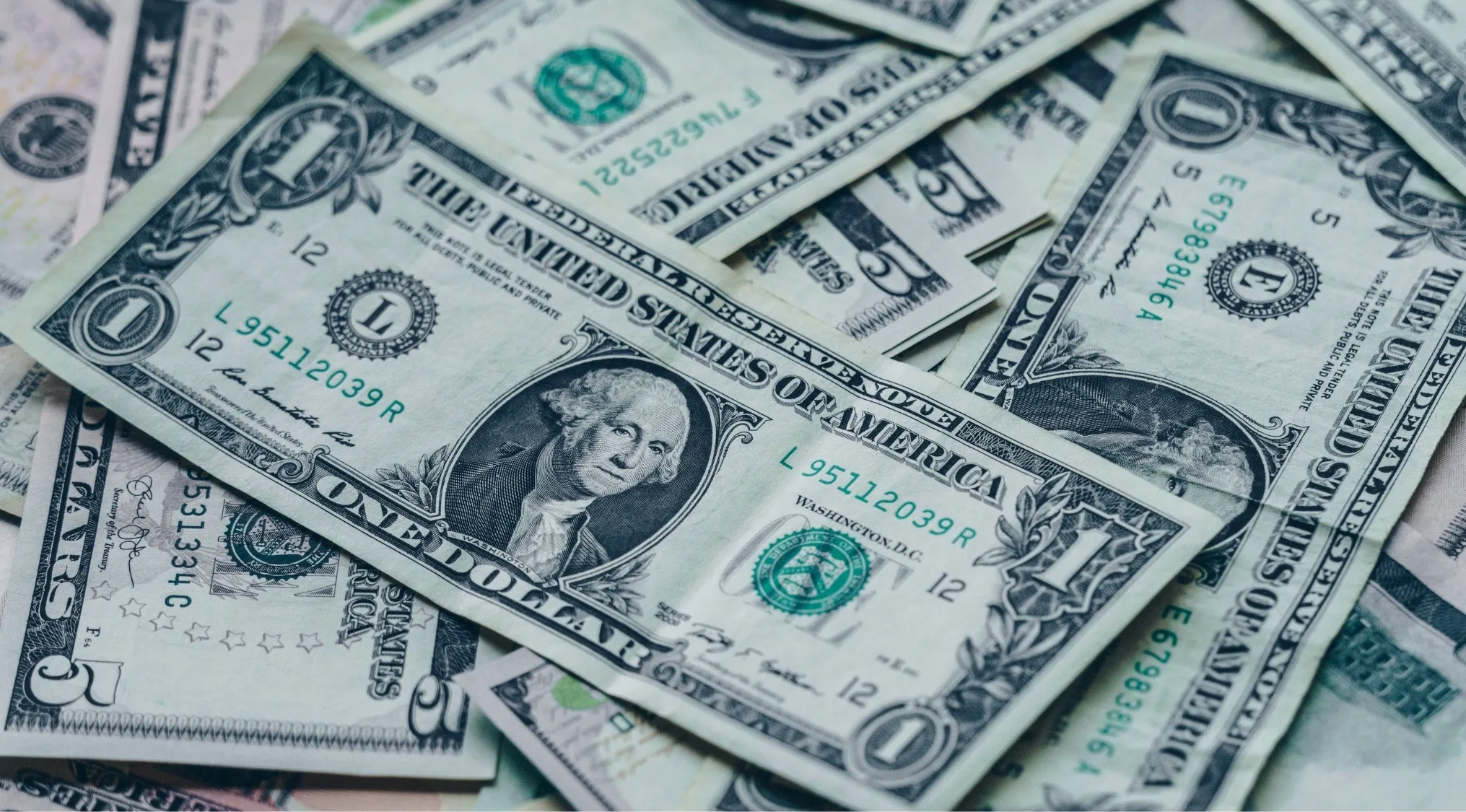 A close-up of scattered US dollar bills, emphasizing the financial aspect of the 1895 Kansas 8th Grade Arithmetic Exam.