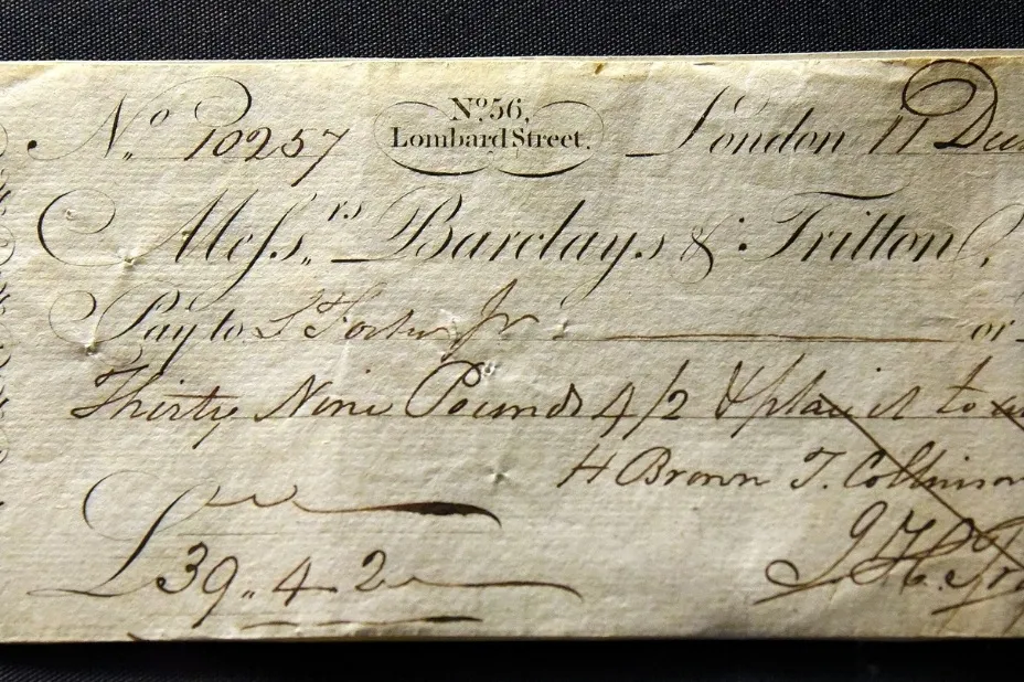 Close-up of an old (bank check) with handwritten text and a date, showing historical banking details.