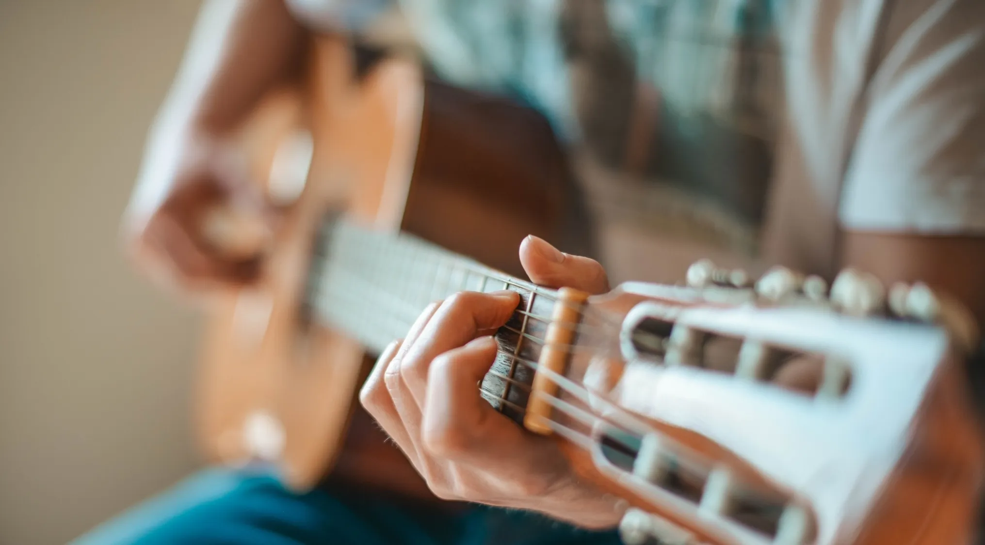A person playing an acoustic guitar, focusing on the distance between two musical notes. General music knowledge.