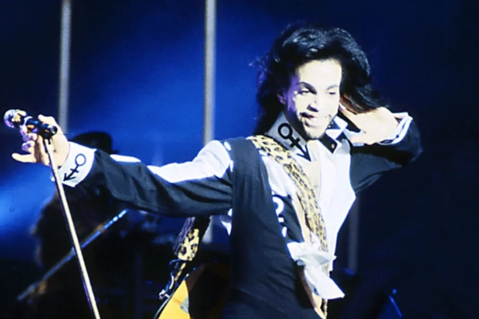 Prince, a renowned singer, performing on stage with a microphone.