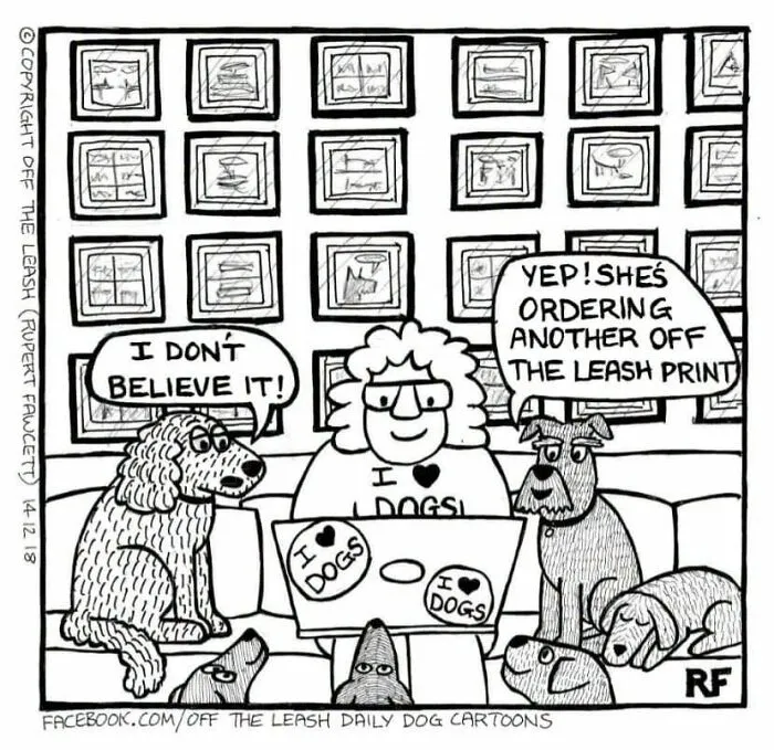 A human happily sits at a laptop with several dog cartoons on it, surrounded by dogs.