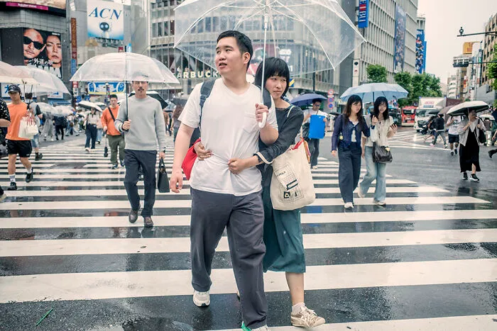 People crossing a wet street with umbrellas in Japan, showcasing dynamic street photography opportunities.