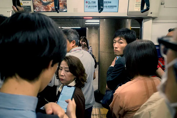 Commuters on a crowded Tokyo subway train, capturing the bustling daily life for street photographers in Japan.