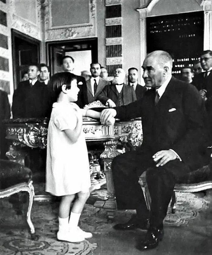 Historic photo of world leader warmly engaging with a child in a formal room